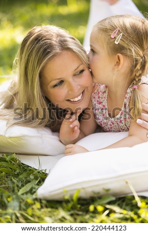 Mother and daughter relaxing cuddling in garden