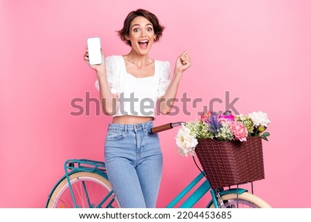 Photo of cute lucky lady wear white crop top riding bike showing modern gadget empty space isolated pink color background