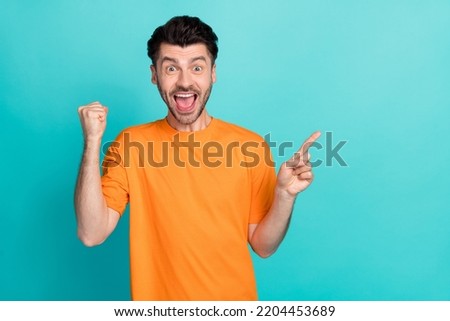 Photo of young attractive handsome excited funny student guy showing finger pointing empty space sale deal fist up celebrate win isolated on aquamarine color background