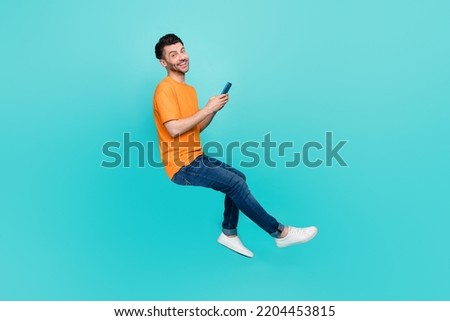 Profile side full body photo of positive guy sit invisible chair blogging device isolated on cyan color background Royalty-Free Stock Photo #2204453815