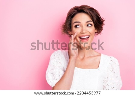 Photo portrait of lovely young girl hands cover mouth look sly empty space wear stylish white garment isolated on pink color background