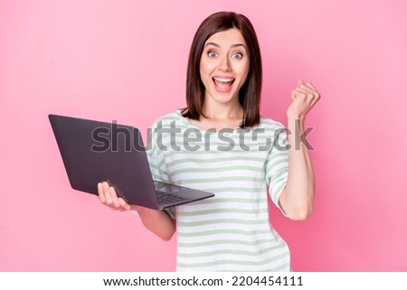 Photo portrait of stunning young girl raise fist win online casino laptop dressed stylish striped clothes isolated on pink color background