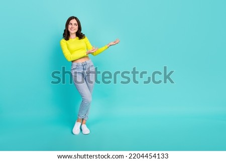 Full length photo of young pretty cute woman palms interested minded looking empty space showing information ad isolated on cyan color background