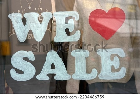 The shop window says "we love sale".