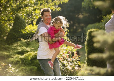Father lifting and carrying his daughter in garden