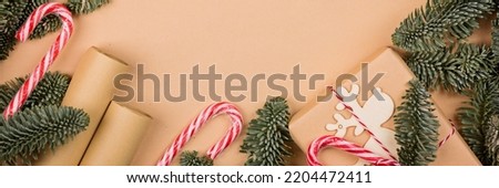 Christmas composition. gift box wrapped in craft paper, fir tree branches, candy canes. new year concept. Greeting card, xmas celebration 2022. Flat lay, top view, copy space, mockup