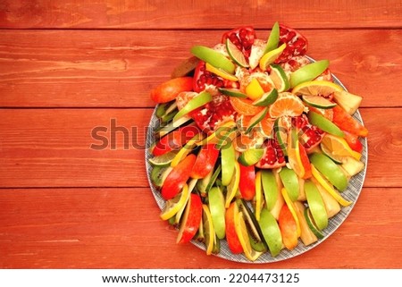 The concept of assorted crushed apple fruits. Slice the pomegranate, lemon, kiwi, pear, orange and put it on a plate. fruit and vegetable salad. on a wooden background. space for text. Still life. 