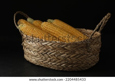 Corn cobs in basket on black table