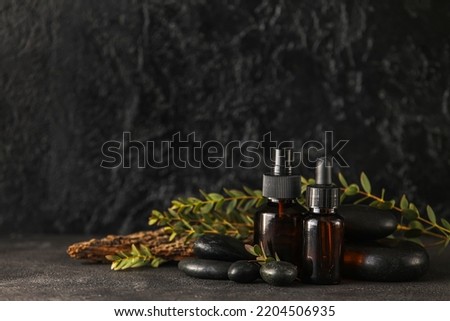 Composition with bottles of cosmetic products, spa stones and eucalyptus branches on dark background