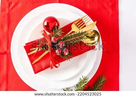 Serving a Christmas table with a set of white plates, gold table surfs and Christmas napkin decorations. top view.