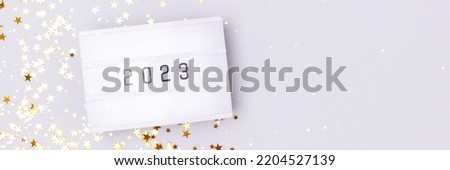 Banner with lightbox with 2023 numbers on a blue background with golden stars confetti. Copy space.