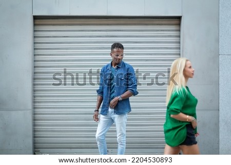 Scene of an african man looking at a blonde woman as she pass in the street Royalty-Free Stock Photo #2204530893