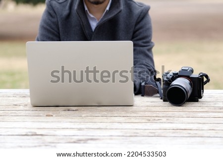 Male photographer operating a personal computer outdoors