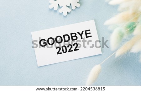 Goodbye 2022 text on a card on a blue background, business concept