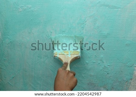 someone is painting a wall with a brush using a turquoise color 