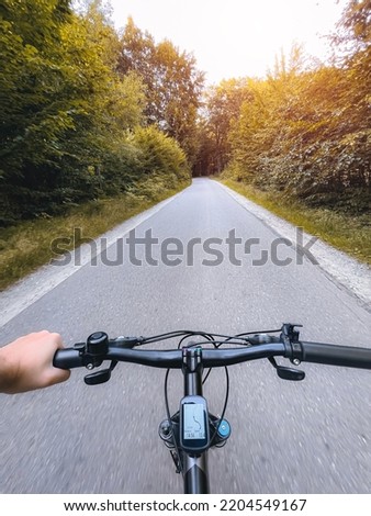 Close up of bicycle handle bar. First-person view of bicycle riding. Man riding a bike. Holding bike handlebar with one hand. Summertime outdoor leisure sport activity. Royalty-Free Stock Photo #2204549167