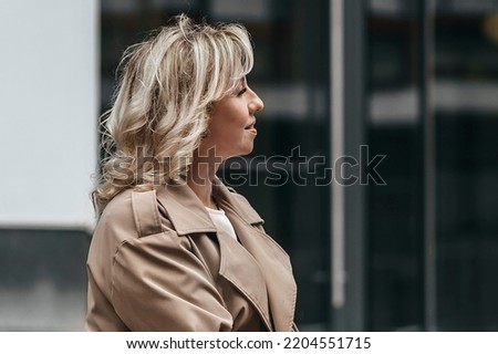 Portrait of a middle-aged blonde woman with curly hair on a city street