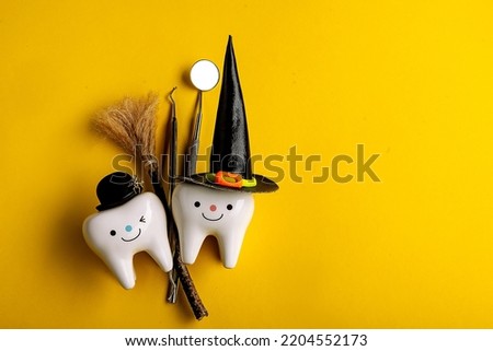 
dental concept. tooth figurine in halloween costume and dental tools. pumpkins and a broom. on a yellow background