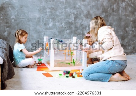 Female teacher with little creative children learn to paint rainbow and nature. Having fun in kid development childcare center. Nursery school and early education. Little artists, art hobby activity