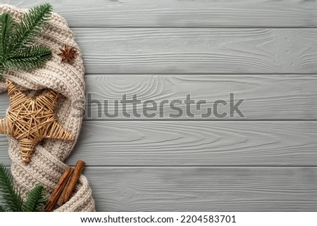 Winter holidays concept. Top view photo of wicker star knitted scarf pine branches anise and cinnamon sticks on grey wooden desk background with empty space