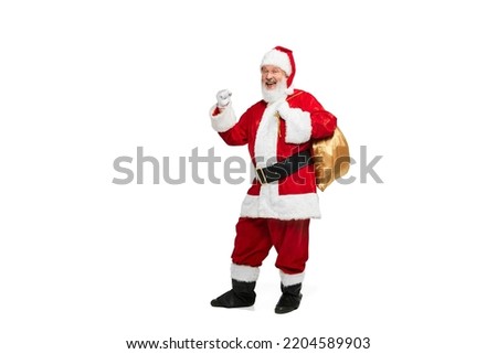 Portrait of senior man in image of Santa Claus posing with big golden box for presents isolated over white background. Concept of fictional character, holiday, New Year, Christmas. Copy space for ad