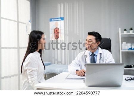 Asian woman patient visit and consult health problem with young doctor. Attractive therapist practitioner work to explain diagnosis in office hospital to give treatment to sick girl during appointmen Royalty-Free Stock Photo #2204590777
