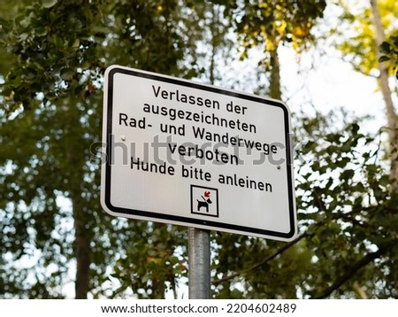 German sign that says that it is forbidden to go out of the paths and dogs should be kept on a leash. White information sign on a trail in the nature. Rules of conduct for people on the footpath.