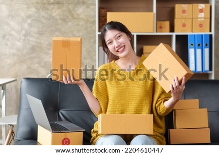 Beautiful Asian online business owner is preparing a parcel box to prepare the package for delivery to the customer. Check the list of items and the shipping address is correct.