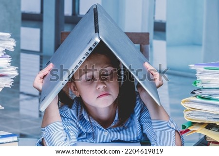 Conceptual portrait of angry and exhausted young business girl working overtime alone in office with large amount of documents without cariere perspective and additional payments. 