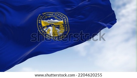 The Nebraska state flag waving in the wind. Nebraska is a state in the Midwestern region of the United States. Royalty-Free Stock Photo #2204620255