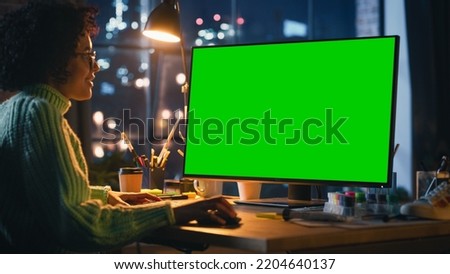 Creative Black Woman Sitting at Her Desk, Using Desktop Computer with Mock-up Green Screen Chromakey. Female Specialist Using Mouse, Scrolling Through Objects, Adding New Elements. Freelance Concept.