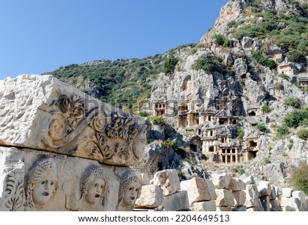 Historical stone theatrical masks bas relief of amphitheater on the background of rock-cut tombs of necropolis in the ancient lycian city of Myra. Territory of modern Demre city,Antalya province,Turk