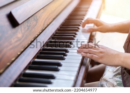 Close-up of hands woman wearing brownish green dress stylish hipster with playing old wooden piano Vintage classic style.