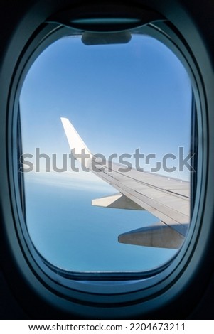 View from the inside or interior of the airplane. Airplane porthole window view from the passenger seat Royalty-Free Stock Photo #2204673211