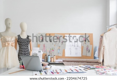 Workplace of dressmaker and designer seamstress tailor with the dummy mannequin, sewing machine, laptop, thread, sketches, and other in fashion design studio. Lifestyle and creative clothing concept.