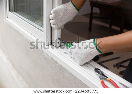 Construction worker repairing the sliding window. Royalty-Free Stock Photo #2204683975