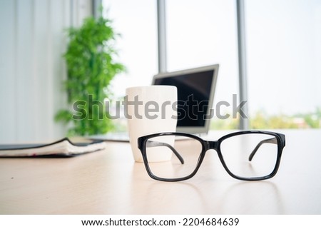 Stationay glasses and laptop on wood table in business office copy space