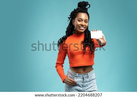 Girl holding a gift card. Young beautiful woman showing copy space on empty blank sign or gift card isolated on blue background