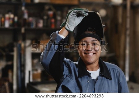 Closeup portrait of smiling female welder looking at camera in industrial factory, copy space Royalty-Free Stock Photo #2204693293