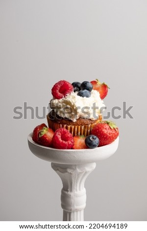 Beautiful muffin with delicious vegan cream, fresh berries on a decorative white pad . Place for your text. Sweet concept. Excellent image for dessert banners and advertisements. Desert background. 