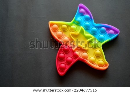 A children's toy made of rubber in the shape of a colorful star. Isolated a rubber star on black background.