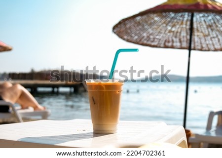 Ice latte coffee in plastic glass on the beach.