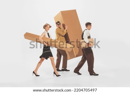 Portrait of young stylish people carrying giant cardboard boxes isolated over white background. Black Friday shopping, sales, moving. Concept of retro fashion, style, youth culture, emotions, ad