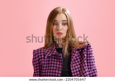 Portrait of young beautiful woman in classical suit posing isolated over pink studio background. Long lashes. Concept of beauty, lifestyle, youth, emotions, facial expression, ad.