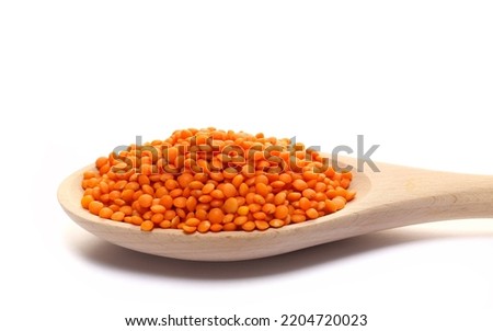 Red lentils pile in wooden spoon  isolated on white  