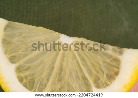 A slice of lemon closeup. On a green background. View from above
