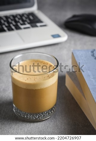 Latte, book, laptop with mouse on workplace desk.