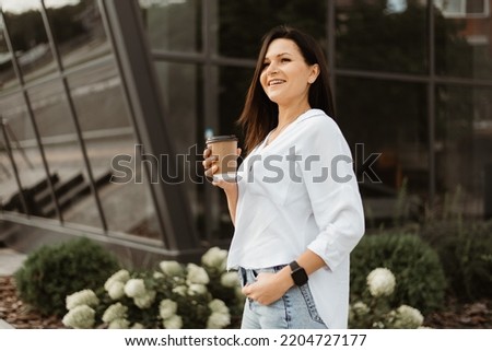 Young woman using smartphone and drinking coffee at the city.