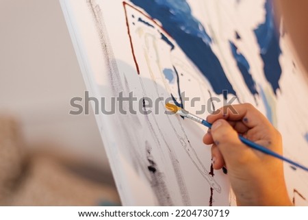 A boy draws a picture with paints and a brush