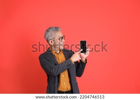 The senior Asian business man standing on the ornage background.